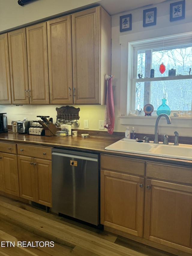 kitchen featuring visible vents, wood finished floors, dishwasher, a sink, and dark countertops