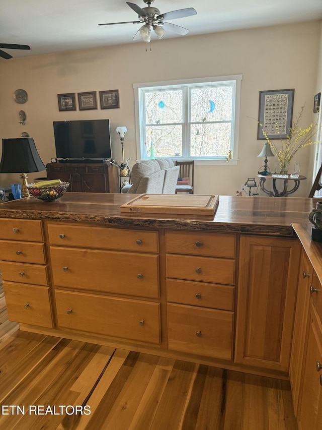kitchen featuring dark countertops, brown cabinets, wood finished floors, and ceiling fan
