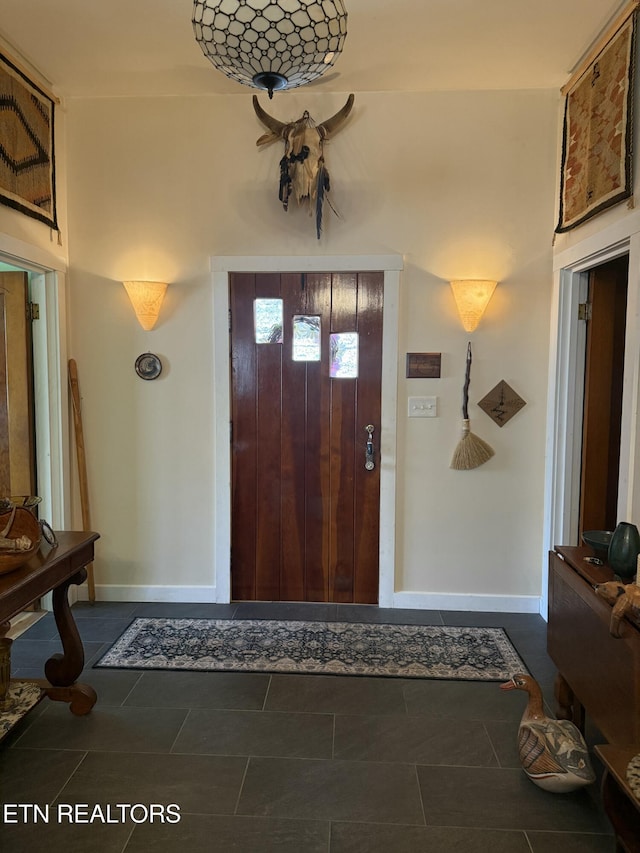 foyer with dark tile patterned flooring and baseboards