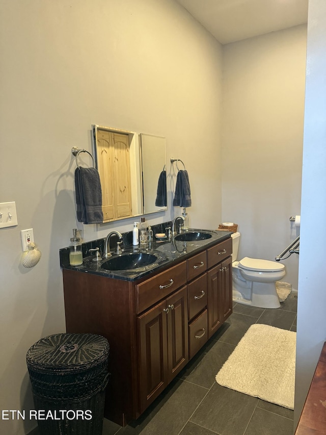 bathroom with tile patterned floors, double vanity, a sink, and toilet