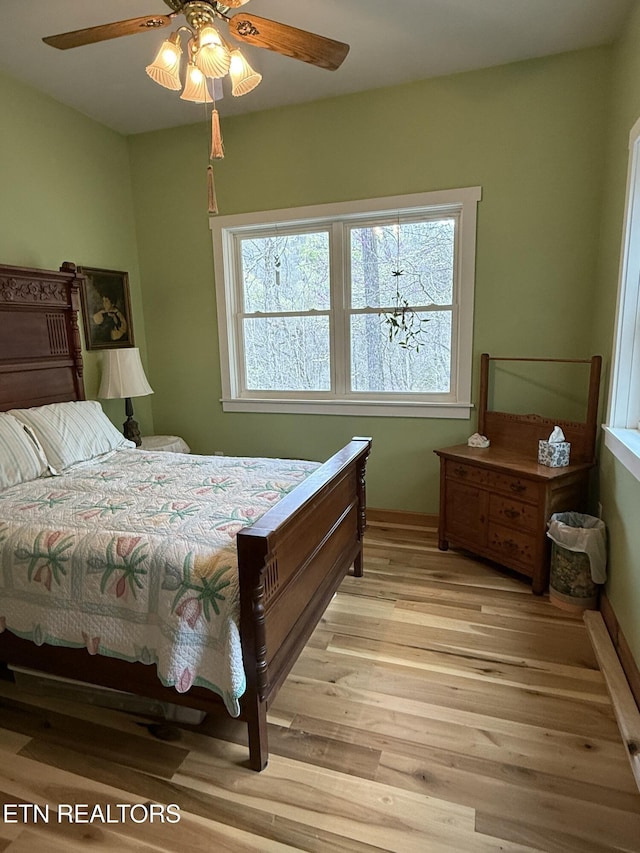 bedroom with light wood finished floors, baseboards, and a ceiling fan