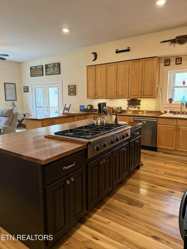 kitchen featuring recessed lighting, butcher block counters, light wood-style floors, stainless steel appliances, and a sink