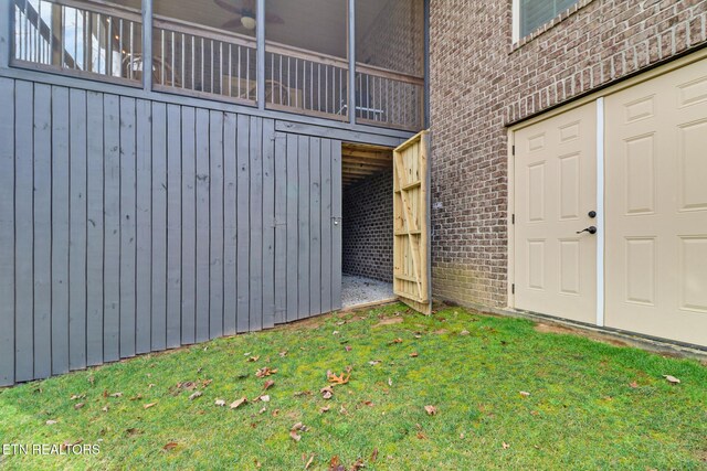 view of exterior entry with brick siding and a yard