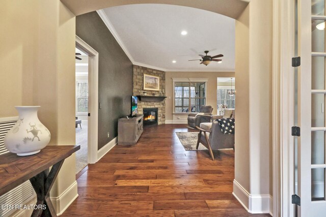 interior space featuring ornamental molding, arched walkways, baseboards, and wood finished floors
