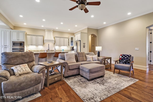 living room with dark wood-style floors, arched walkways, baseboards, and a ceiling fan