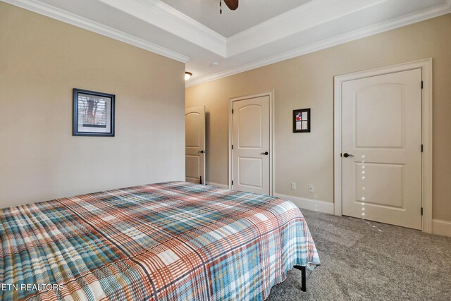 bedroom with a tray ceiling, ornamental molding, carpet, baseboards, and ceiling fan