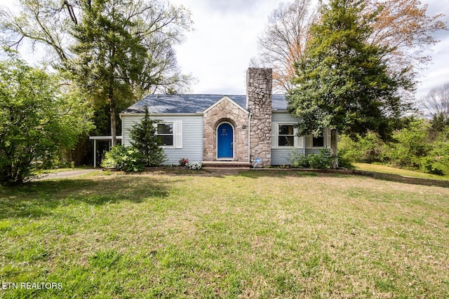 ranch-style home featuring a chimney, a front yard, and stone siding