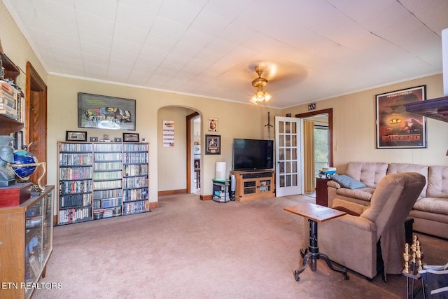 living room featuring carpet flooring, arched walkways, crown molding, and ceiling fan