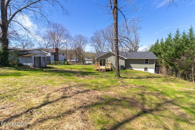 view of yard with an outbuilding, a shed, fence, and a wooden deck