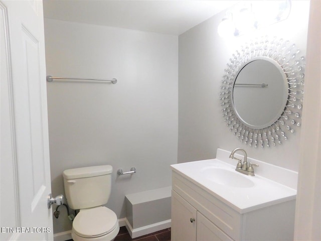 bathroom with toilet, vanity, and baseboards
