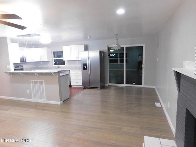 kitchen with a peninsula, stainless steel appliances, visible vents, white cabinets, and ceiling fan
