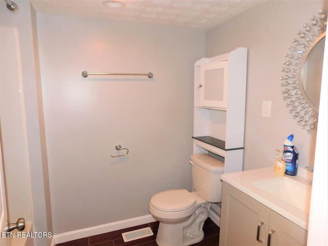 bathroom with baseboards, visible vents, toilet, and vanity