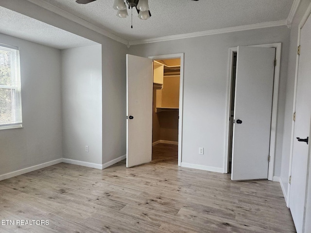 unfurnished bedroom with crown molding, a textured ceiling, wood finished floors, and baseboards