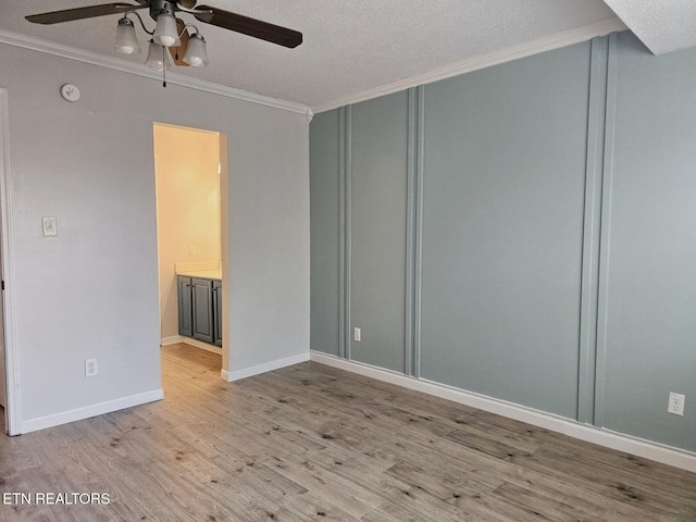 unfurnished room with a textured ceiling, baseboards, ceiling fan, crown molding, and wood finished floors