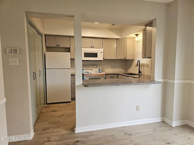 kitchen featuring white appliances, decorative backsplash, light wood-type flooring, and a sink