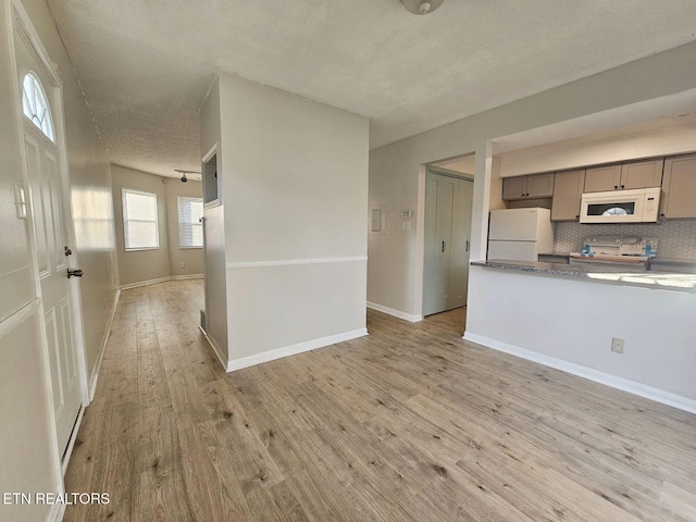kitchen featuring gray cabinetry, a textured ceiling, white appliances, tasteful backsplash, and light wood-type flooring