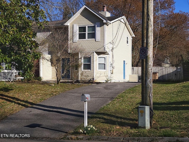 view of front of home featuring fence, driveway, a chimney, and a front yard