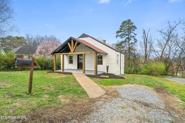 bungalow-style house featuring a chimney, covered porch, and a front yard