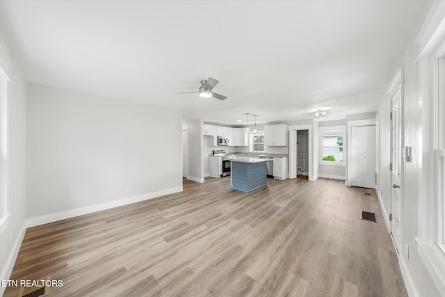 unfurnished living room with ceiling fan, baseboards, visible vents, and light wood-style flooring