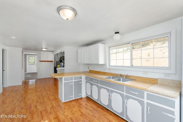869 Poplar Grove Rd, Harrogate, TN 37752 - kitchen with a sink, a peninsula, light wood-type flooring, light countertops, and white cabinetry