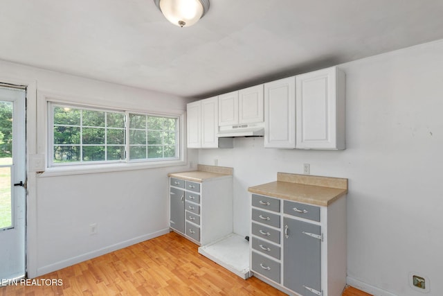 869 Poplar Grove Rd, Harrogate, TN 37752 - kitchen with under cabinet range hood, white cabinets, light wood-style flooring, baseboards, and light countertops
