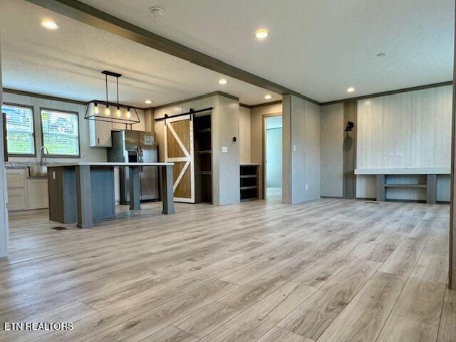 interior space featuring open floor plan, light wood-style flooring, stainless steel fridge, and a barn door
