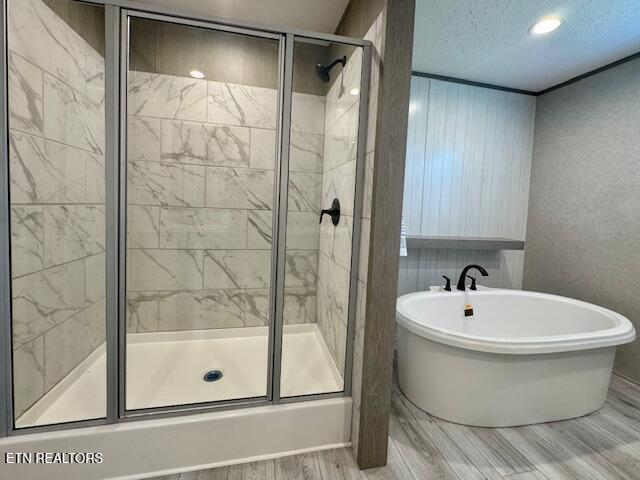 bathroom with a textured ceiling, a stall shower, and a freestanding bath