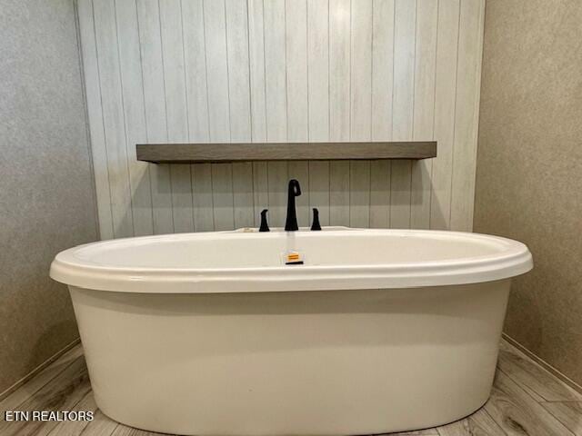 full bath with a freestanding bath and wood finished floors