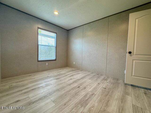 empty room with wood finished floors and a textured ceiling