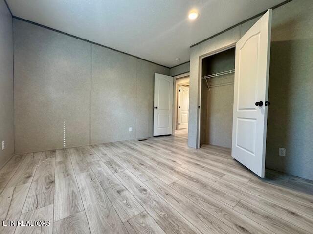 unfurnished bedroom with a closet and light wood finished floors