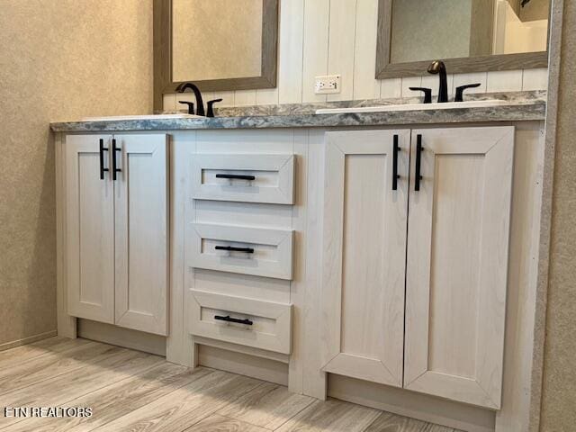 full bathroom featuring a sink, double vanity, and wood finished floors