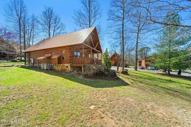 view of side of home with a lawn, metal roof, and log exterior