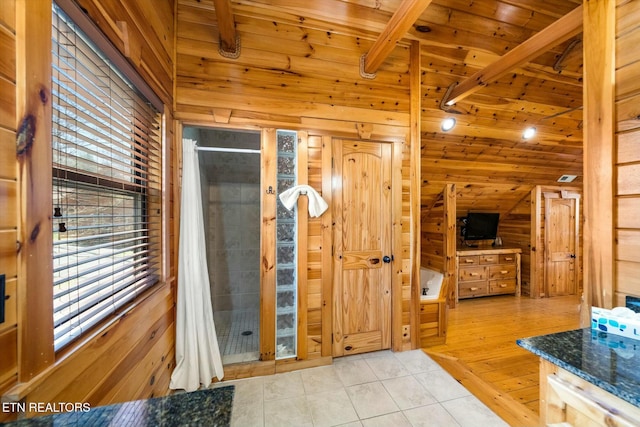 bathroom with tile patterned floors, wood ceiling, a shower stall, vaulted ceiling with beams, and wooden walls
