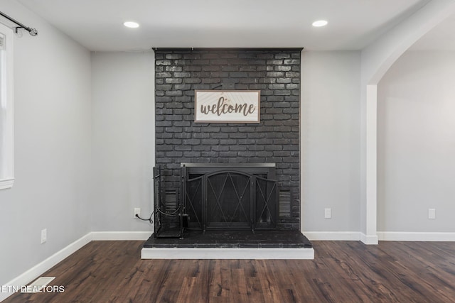 room details with recessed lighting, baseboards, arched walkways, a fireplace, and wood finished floors