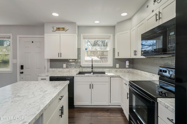 kitchen featuring a healthy amount of sunlight, a sink, black appliances, and dark wood finished floors