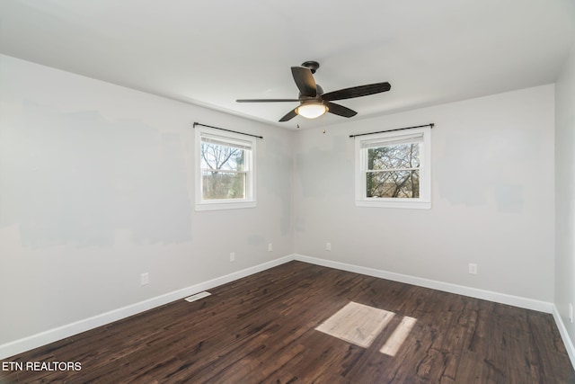 unfurnished room with baseboards, ceiling fan, visible vents, and dark wood finished floors