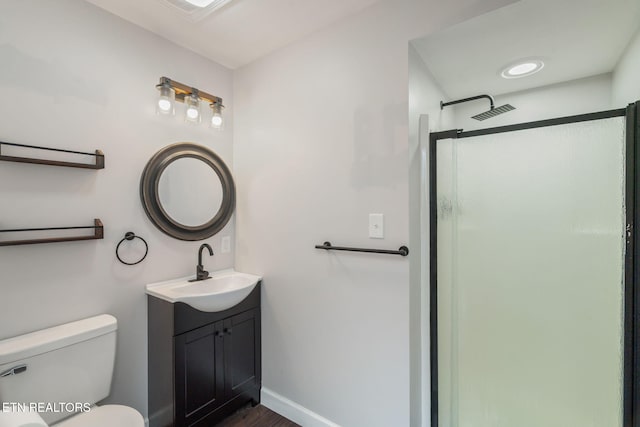 full bath featuring toilet, vanity, a stall shower, and baseboards