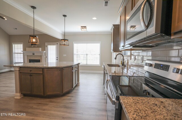 kitchen with a sink, stainless steel appliances, visible vents, ornamental molding, and a healthy amount of sunlight