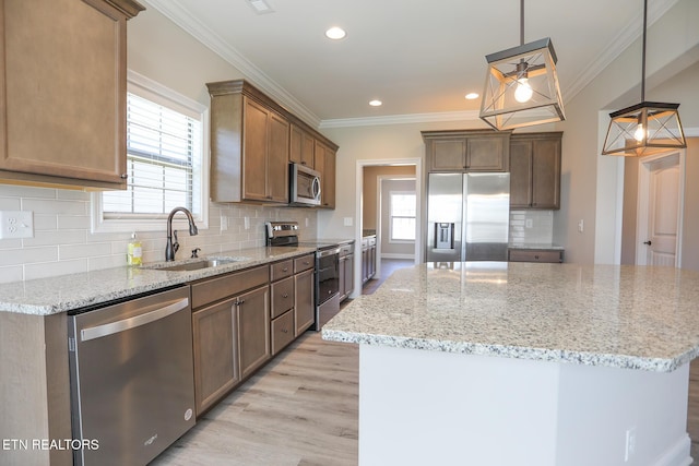 kitchen with light wood-style flooring, ornamental molding, a sink, and stainless steel appliances