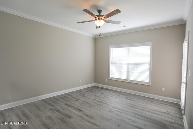 spare room with crown molding, baseboards, visible vents, ceiling fan, and wood finished floors