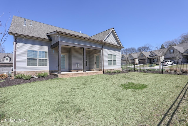 exterior space with a lawn, a shingled roof, and fence