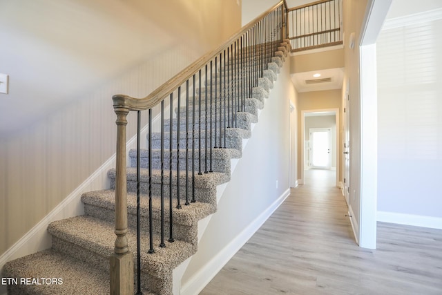 stairs with baseboards, visible vents, wood finished floors, and a towering ceiling