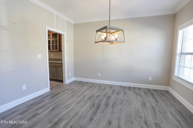 unfurnished room featuring light wood finished floors, baseboards, ornamental molding, and a healthy amount of sunlight