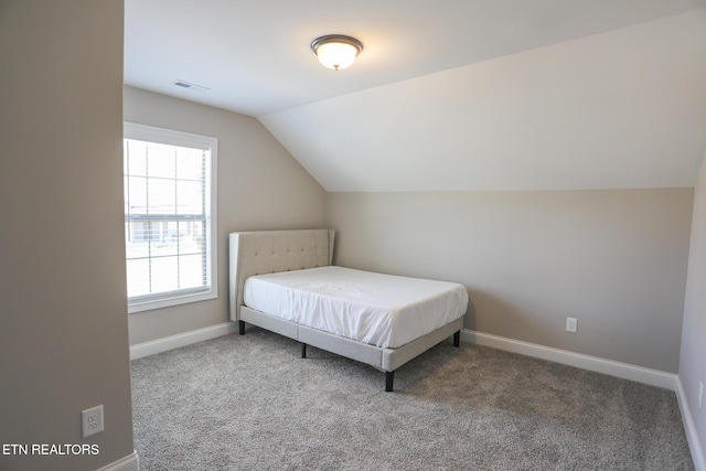 carpeted bedroom featuring baseboards, lofted ceiling, and visible vents