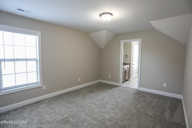 bonus room featuring baseboards, visible vents, vaulted ceiling, and light colored carpet
