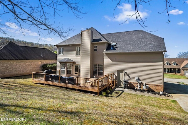 rear view of property with a chimney, a yard, and a wooden deck