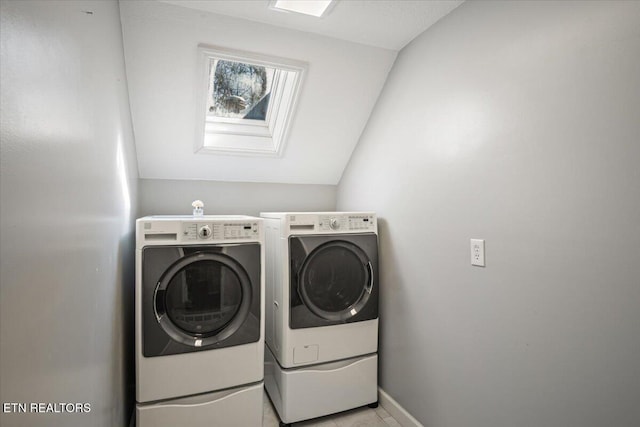washroom with a skylight, baseboards, separate washer and dryer, and laundry area