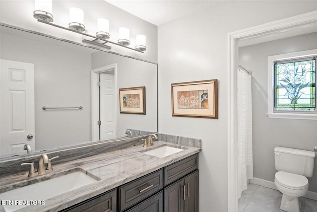 full bath featuring toilet, a sink, double vanity, and tile patterned floors