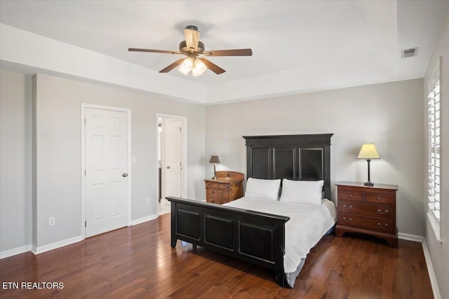 bedroom featuring visible vents, baseboards, a ceiling fan, a raised ceiling, and hardwood / wood-style floors