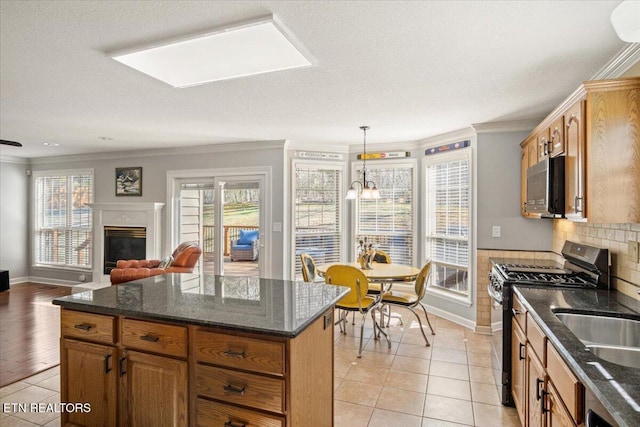 kitchen featuring a glass covered fireplace, ornamental molding, light tile patterned floors, and gas stove